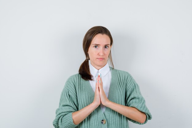 Free photo young woman showing namaste gesture in blouse, cardigan and looking focused. front view.