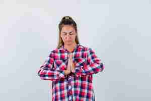 Free photo young woman showing namaste gesture in casual shirt and looking hopeful. front view.