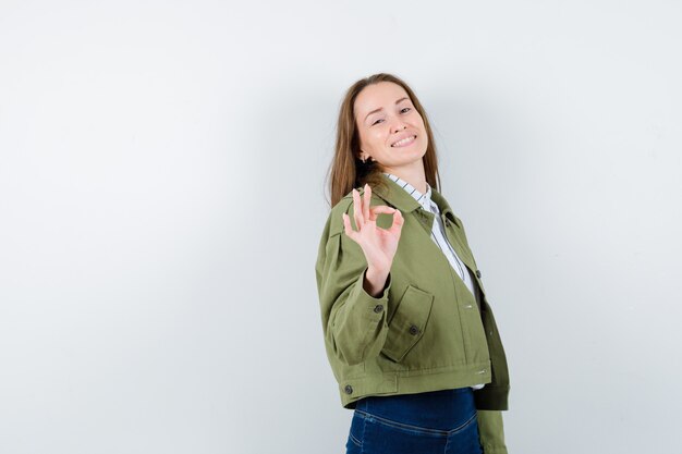 Free photo young woman showing ok gesture in shirt, jacket and looking confident. front view.