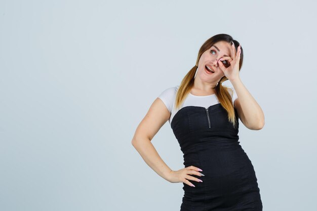 Young woman showing ok sign on eye