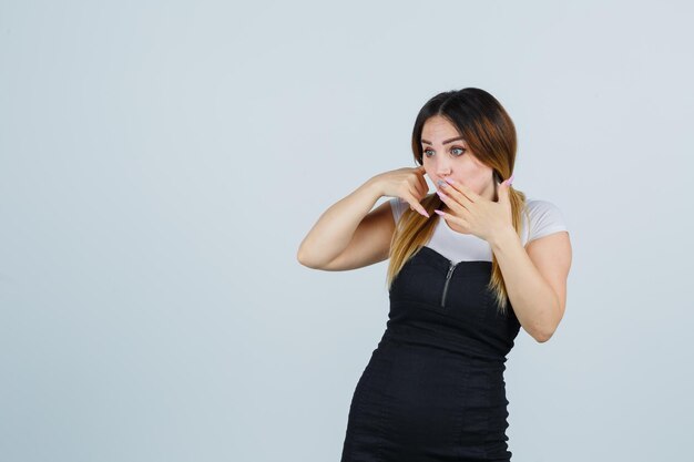 Young woman showing phone gesture and looking surprised