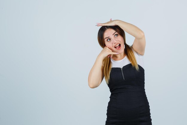 Young woman showing phone gesture while holding hand on head