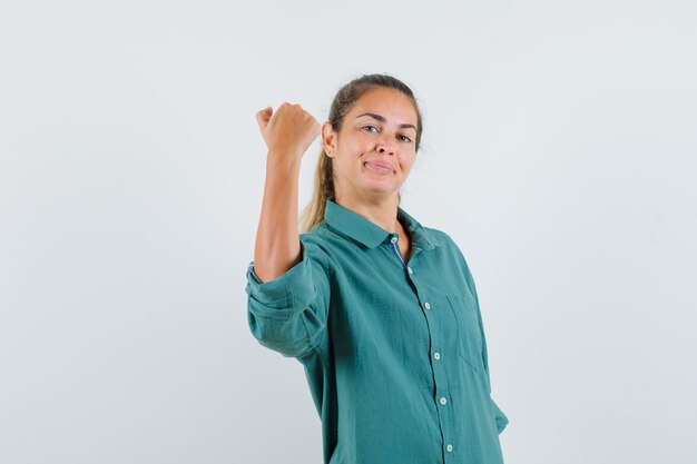 Young woman showing power gesture in green blouse and looking confident