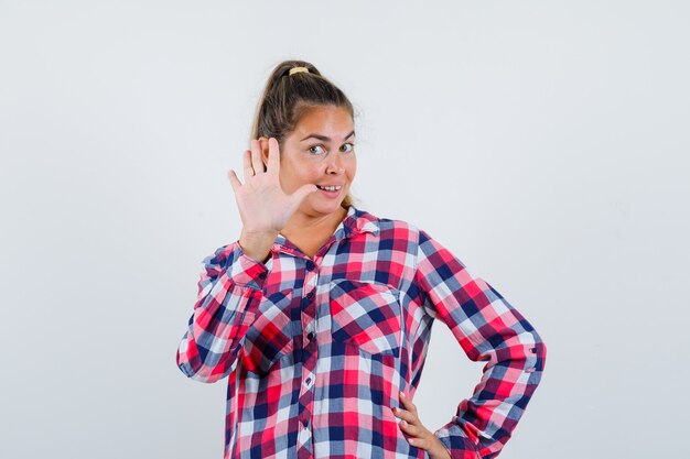 Young woman showing refusal gesture in casual shirt and looking cheerful , front view.