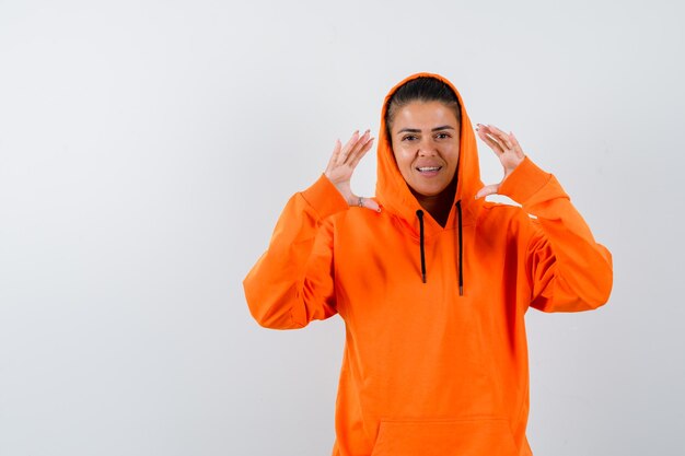 Young woman showing scales in orange hoodie and looking beautiful 