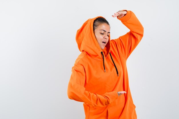 Young woman showing scales in orange hoodie and looking focused