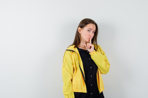 Young woman showing silence gesture and looking serious