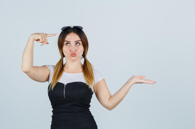 Young woman showing something while pointing at glasses