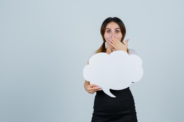 Young woman showing speech bubble while holding hand on mouth