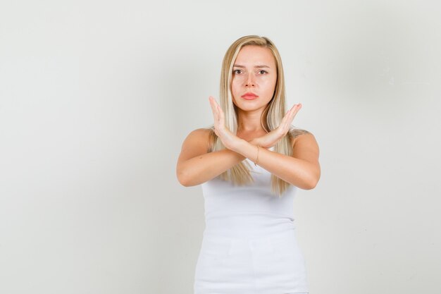 Молодая женщина показывает жест остановки в синглете и выглядит расстроенным.