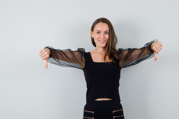 Young woman showing thumb down in black blouse 