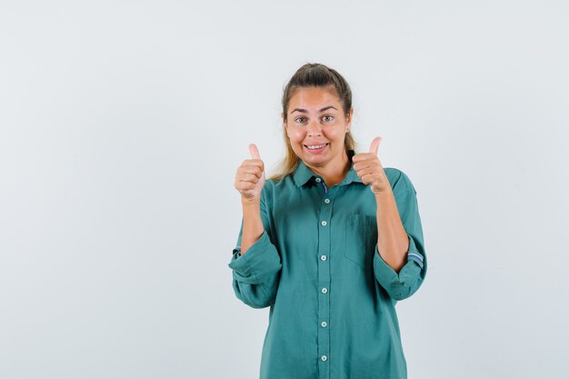 Young woman showing thumb up in blue shirt and looking pleased