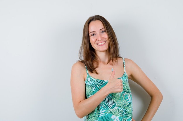 Free photo young woman showing thumb up and looking merry , front view.