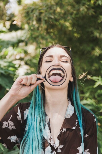 Young woman showing tongue through magnifying glass