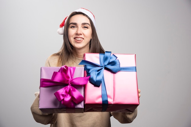 크리스마스 선물 두 상자를 보여주는 젊은 여자.