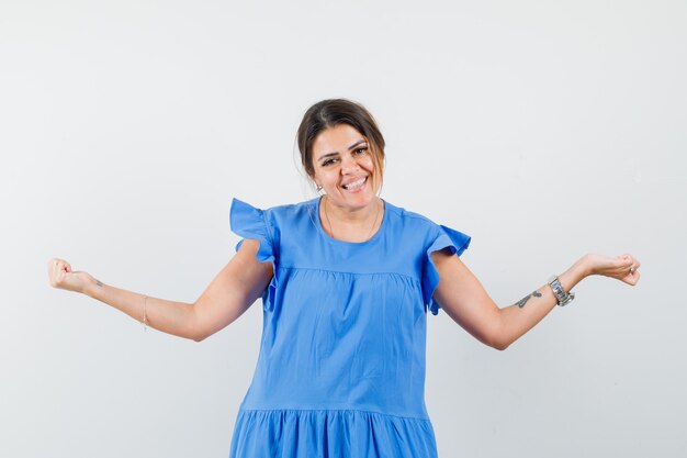 Young woman showing winner gesture in blue dress and looking lucky