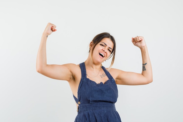 Young woman showing winner gesture in dress and looking happy