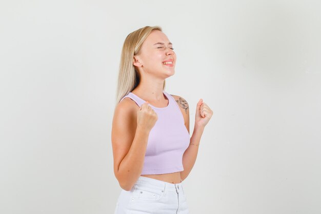 Молодая женщина показывает жест победителя в синглете