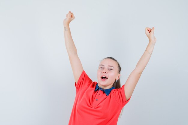 Young woman showing winner gesture in t-shirt and looking blissful
