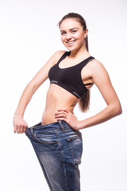 Free photo young woman shows her weight loss by wearing an old jeans