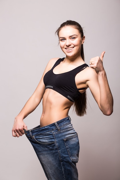 Free photo young woman shows her weight loss by wearing an old jeans