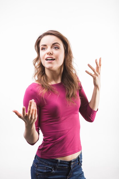 Young woman shrugging against white background