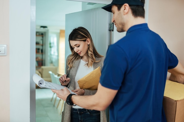 Free photo young woman signing documents while receiving home delivery from a courier