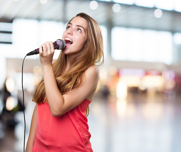 молодая женщина поет с микрофоном на белом фоне