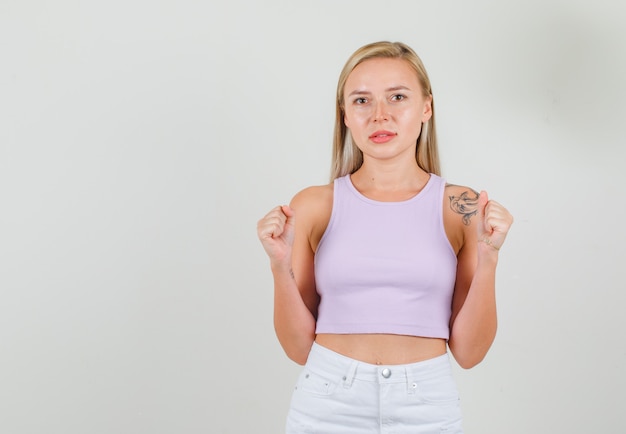 Young woman in singlet, mini skirt standing with clenched fists