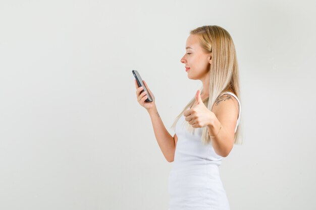 スマートフォンを持っている間親指を表示している一重項の若い女性