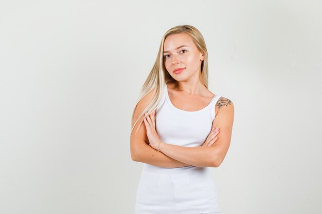 Young woman in singlet standing with crossed arms and smiling 