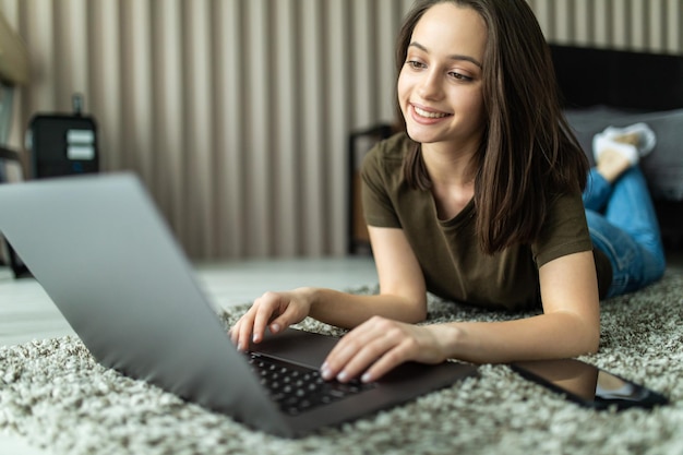 Young woman sit carpet folded use laptop make work management project in room indoors