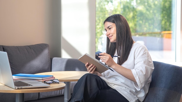 Free photo a young woman sits in front of a laptop and studies remotely