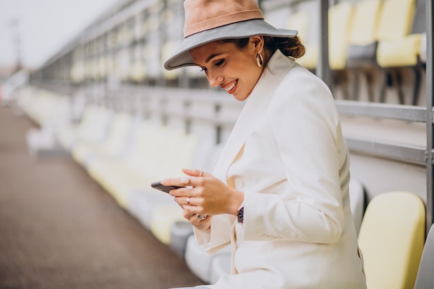 Young woman sitting on arena seats and talking on the phone