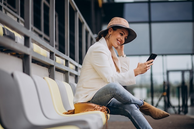 Free photo young woman sitting on arena seats and talking on the phone