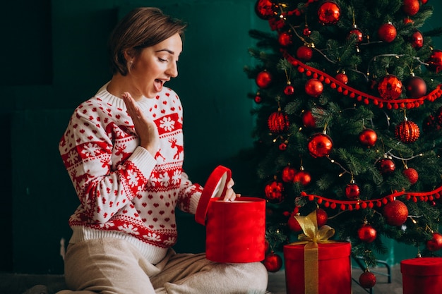 赤いボックスとクリスマスツリーのそばに座っていた若い女性