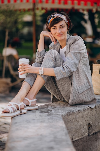 噴水のそばに座ってコーヒーを飲む若い女性