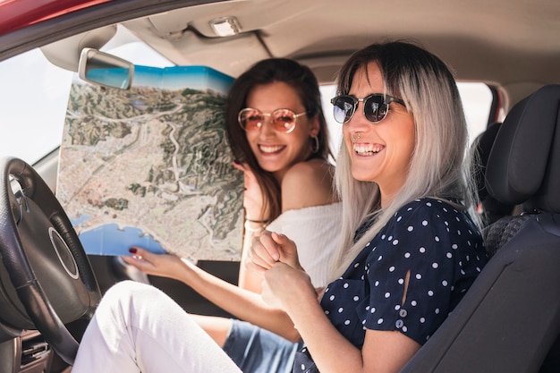 Free photo young woman sitting in the car showing map