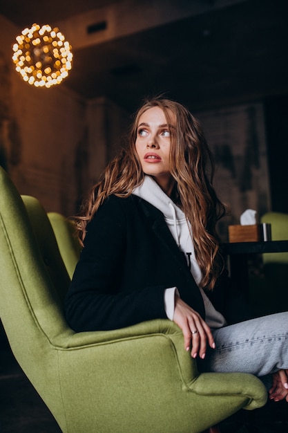 Young woman sitting in a chair inside a cafe