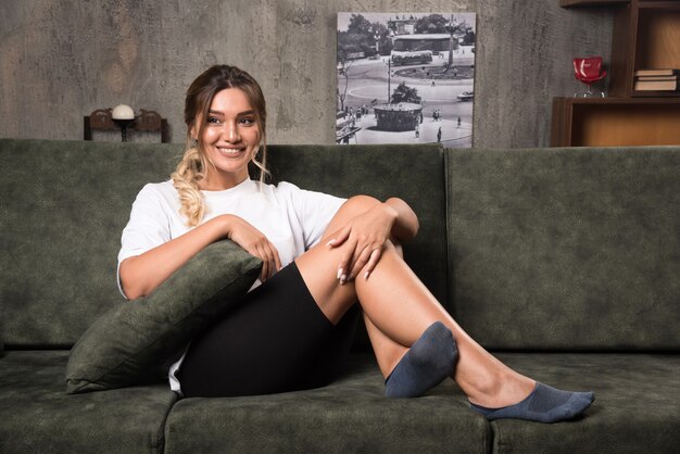 Young woman sitting on couch looking front while smiling.