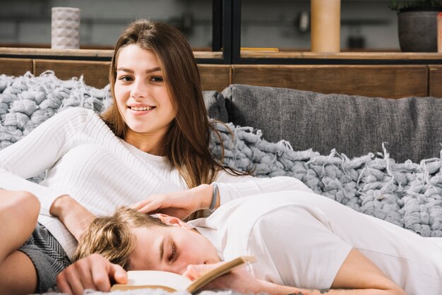 Young woman sitting on couch with sleeping man 