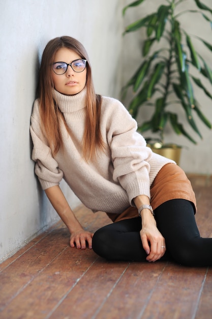 Free photo young woman sitting on the floor and posing