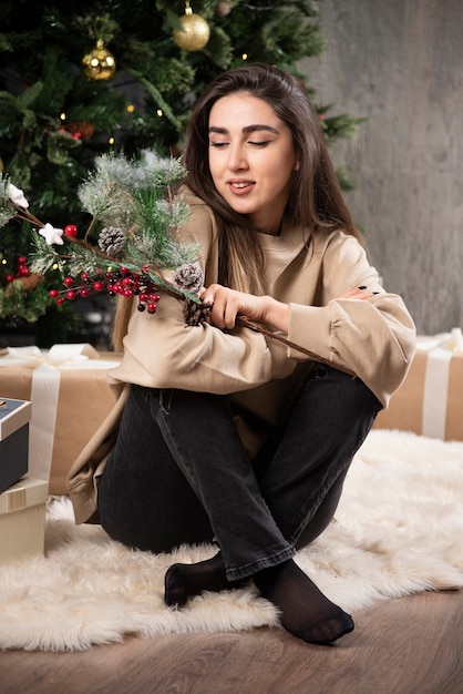 A young woman sitting on fluffy carpet with Christmas holly berries .