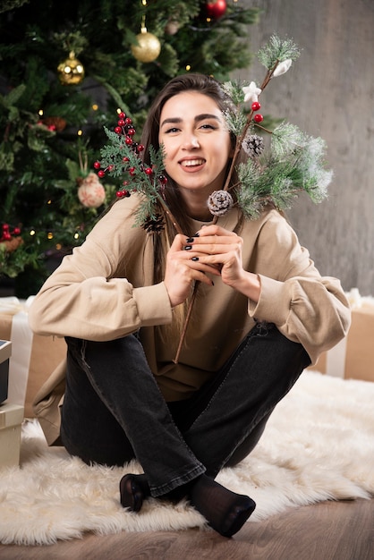 A young woman sitting on fluffy carpet with Christmas holly berries .