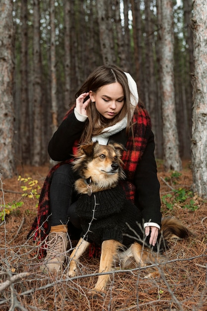 Free photo young woman sitting in a forest with her dog