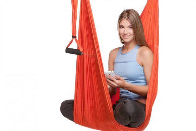 Young woman sitting in hammock for anti-gravity aerial yoga