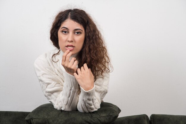 A young woman sitting on her dark green sofa with pillow in hands 