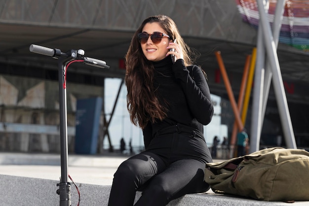 Young woman sitting next to her scooter