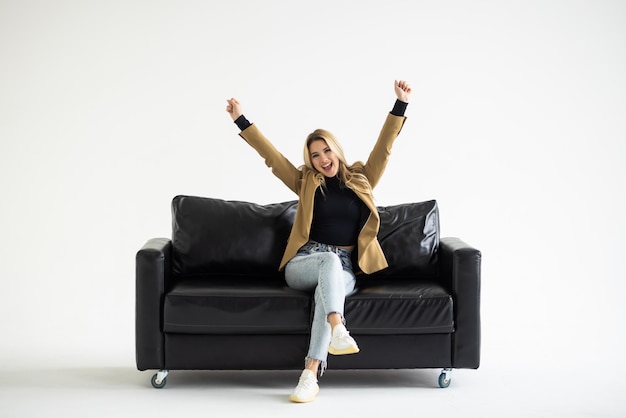 Foto gratuita giovane donna seduta sul suo divano bianco con il computer portatile alla ricerca di un lavoro