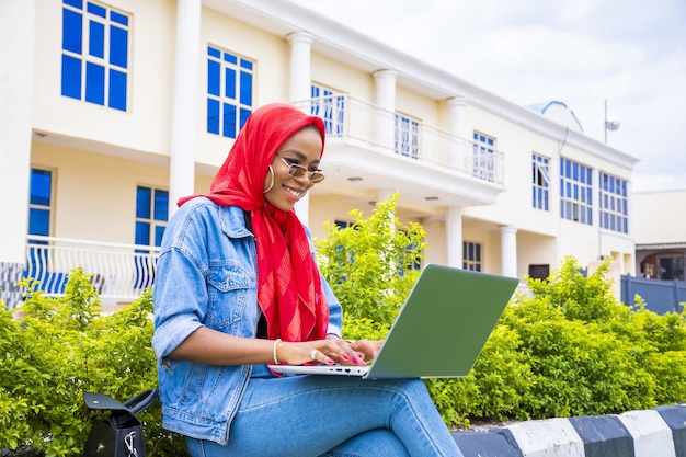 Young woman sitting outside with her laptop and phone